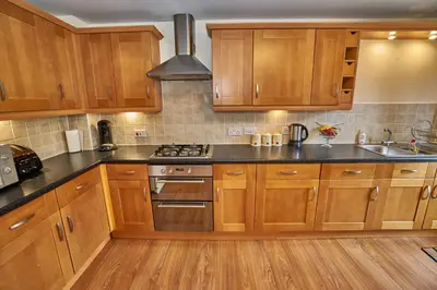 a kitchen with wooden cabinets and a stove top oven at Edinburgh Pearl Apartments - Haymarket Residence in Edinburgh