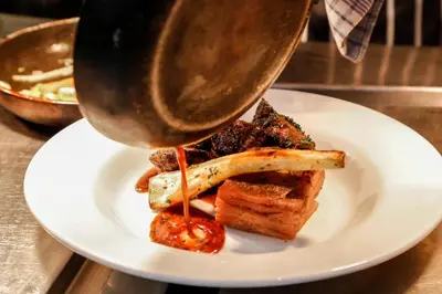 a person is pouring sauce onto a plate of food at Alona Hotel in Motherwell