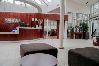 a lobby with a counter and a person in a room at Alona Hotel in Motherwell
