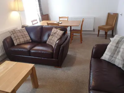 a living room with a leather couch and a table at Blair Drummond Holiday Home in Doune