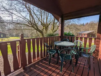 a patio with a table and chairs on a deck at Ruskin Lodges Argyll, by Puck's Glen, Rashfield near Dunoon in Dunoon
