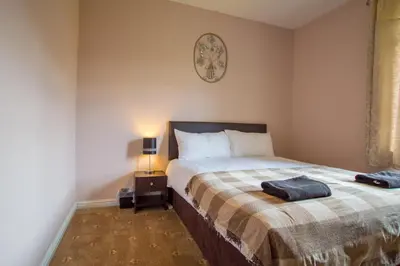 a bedroom with a bed and a clock on the wall at Montgomery Apartments - Stevensons in Edinburgh