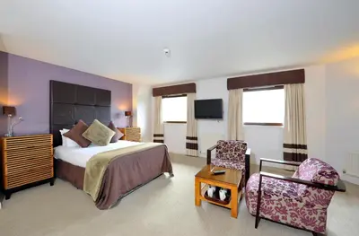 a hotel room with a bed and a chair at Stirling Court Hotel in Stirling