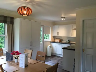 a kitchen with white cabinets and a wooden table at Bruce's Cottage in Stirling