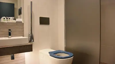 a bathroom with a toilet with a blue seat and a sink at Carlton Hotel in Prestwick