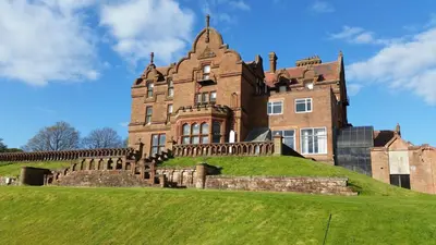 an old castle on top of a grassy hill at Adamton Country House Hotel in Prestwick