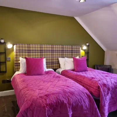two beds in a room with purple blankets and pillows at Rose Villa in Oban