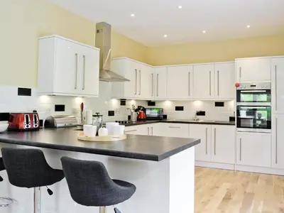 a kitchen with white cabinets and a black counter top at Corrie Massan in Benmore