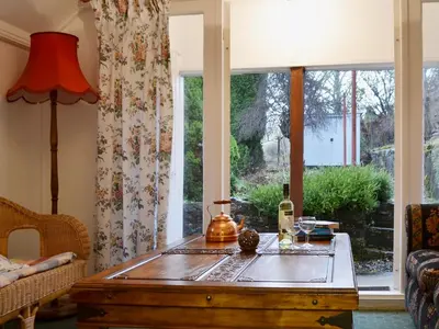 a living room with a table in front of a window at Gracedieu in Killin