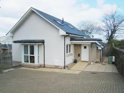 a white house with a roof on a driveway at Bruichladdich in Rothesay