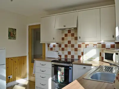 a kitchen with white cabinets and a sink at Baravullin in Benderloch