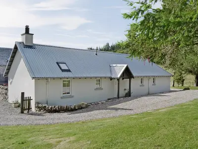 a white house with a metal roof on a gravel driveway at Geordies Byre in Mill of Fortune