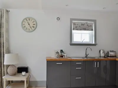 a kitchen with a sink and a clock on the wall at Geordies Byre in Mill of Fortune