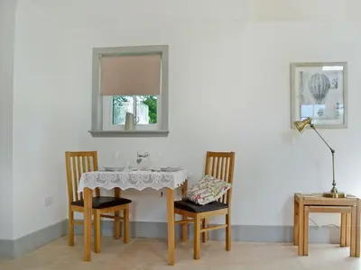 a dining room table with two chairs and a window at Geordies Byre in Mill of Fortune