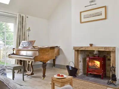 a living room with a piano and a fireplace at Ben Hennie in Mill of Fortune