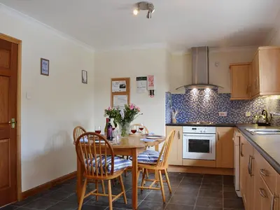 a kitchen with a wooden table and chairs and a kitchen with a stove at Bethany Cottage in Aberfoyle