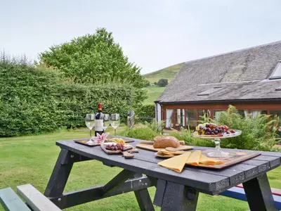 a picnic table with wine glasses and food on it at Old Stones in Glendevon