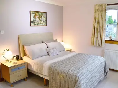 a bedroom with a bed and a nightstand and a window at Eilean Donan in Kirknewton