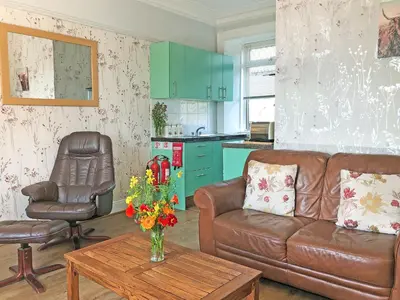 a living room with a couch and a table with flowers at Old Barn Farm Cottage - Cc in Uplawmoor