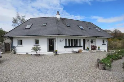 a white house with a roof on a gravel driveway at Bramble Cottage 1, 2 & 3 in Lochdon