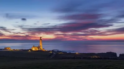 a lighthouse on top of a hill with a sunset at Thornbank House in Stranraer