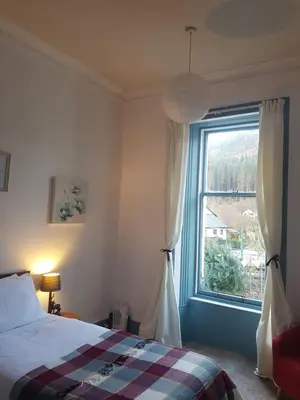 a bedroom with a bed and a window at The Ben Sheann in Strathyre