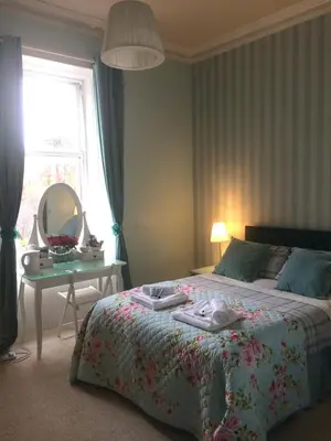 a bedroom with a bed with a mirror and a table at The Ben Sheann in Strathyre