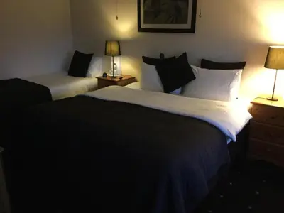 two beds in a hotel room with two lamps at Sandhill House in Troon