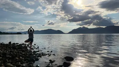 a person standing on the shore of a body of water at Bluebell Cottage with Hot Tub in Ballachulish