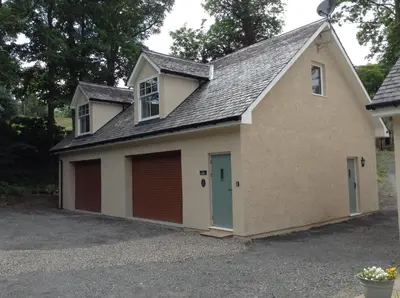 a garage with two garage doors in a driveway at The BurnHowf apartment in Balloch