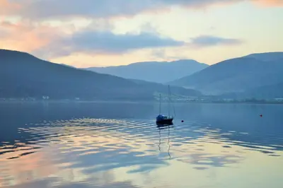 a boat on a lake with mountains in the background at Ardmun House in Dunoon