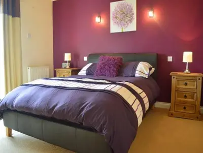 a bedroom with a large bed with purple walls at Clydeside Villa in Dunoon