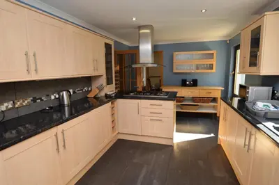 a large kitchen with wooden cabinets and black counter tops at Clydeside Villa in Dunoon