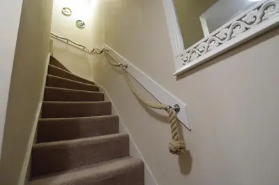 a stairway with a hand rail and a mirror at Newton Cottage South in Inveraray