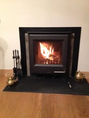 a fireplace sitting on top of a wooden floor at Newton Cottage South in Inveraray