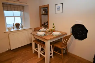 a kitchen with a table and chairs and a window at Newton Cottage South in Inveraray