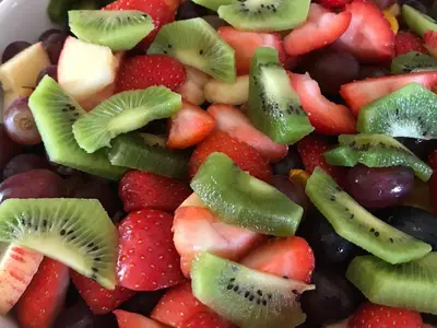 a bowl of fruit with strawberries kiwis and grapes at Crofthead Farm House in Tarbolton