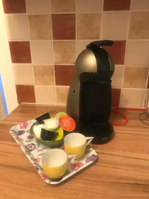 a coffee maker and cups on a plate on a counter at Garden Cottage in Gartocharn