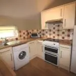 a kitchen with white cabinets and a sink and a stove at Garden Cottage in Gartocharn