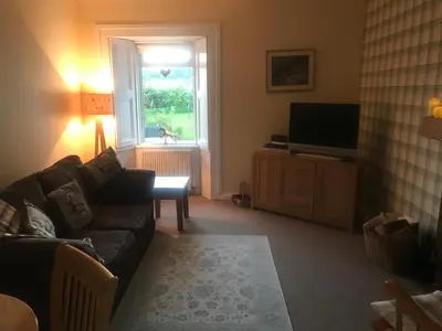a living room with a couch and a television at Garden Cottage in Gartocharn