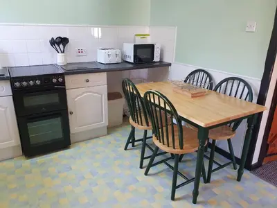 a kitchen with a wooden table and four chairs at Crailloch Croft Cottages in Stranraer