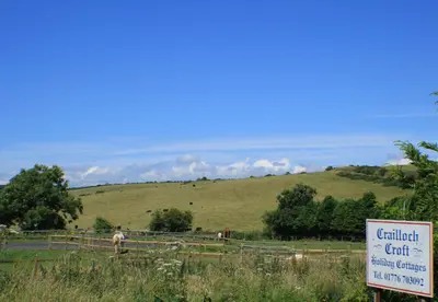 a sign in front of a field with some animals at Crailloch Croft Cottages in Stranraer