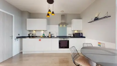 a kitchen with white cabinets and a table and chairs at Glassford Residence in Glasgow