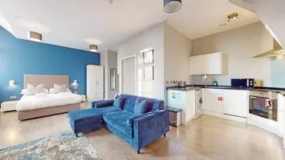 a living room with a blue couch and a bed at Glassford Residence in Glasgow