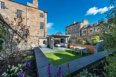 a garden with a table and chairs in front of a building at Garden Rooms Edinburgh in Edinburgh