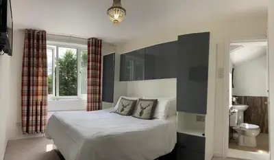 a bedroom with a large bed and a bathroom at Norwood Guesthouse-Loch Lomond in Balloch