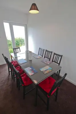 a dining room table with red cushioned chairs and a table with a tableablish at Fonn Na Mara in Campbeltown