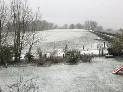 a field covered in snow with a fence and trees at Whiteley's Cottages in Dumbarton