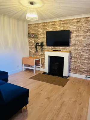 a living room with a fireplace with a flat screen tv at Whiteley's Cottages in Dumbarton