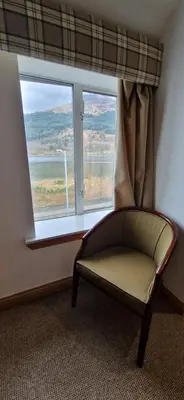 a chair in a room with a large window at Loch Long Hotel in Arrochar